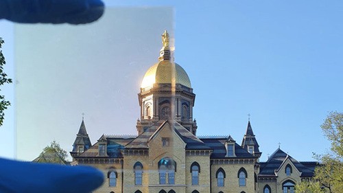 Notre Dame’s Golden Dome partially photographed through a sample (top left) of the TRC window coating.